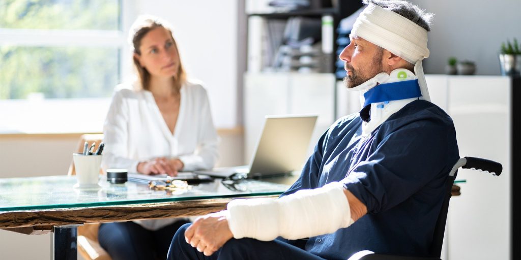 A person with a neck brace and arm cast sitting at a table opposite another person. - Car Accident Claim